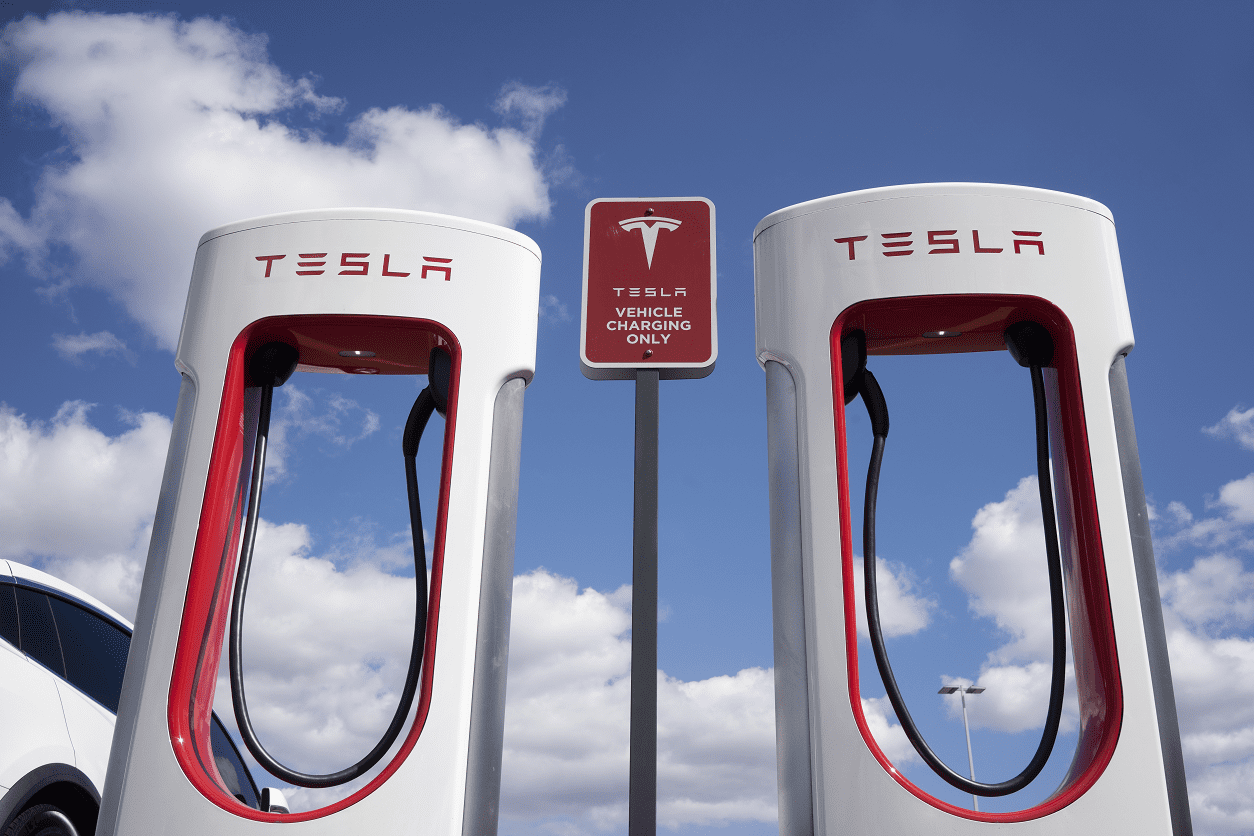 Two tesla charging stations with a sign in the background.