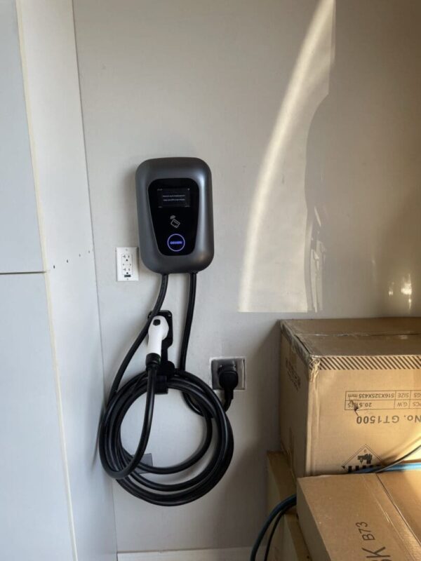 Electric vehicle charger with cord on wall.